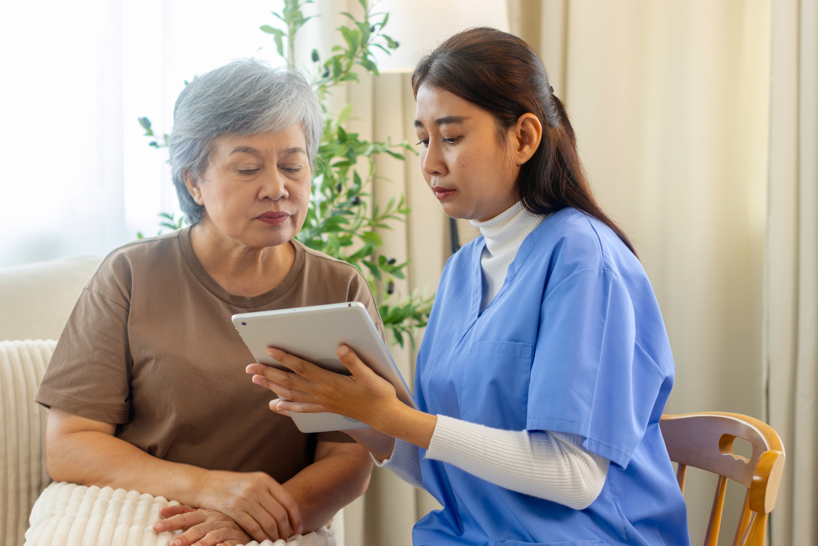 Nurse reviewing healthcare documentation on a tablet with an elderly patient