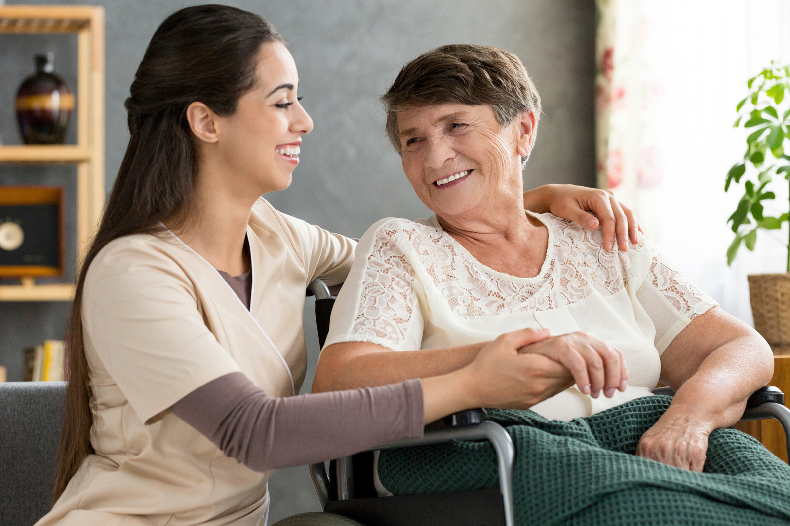 Compassionate caregiver holding hands with an elderly woman in a wheelchair